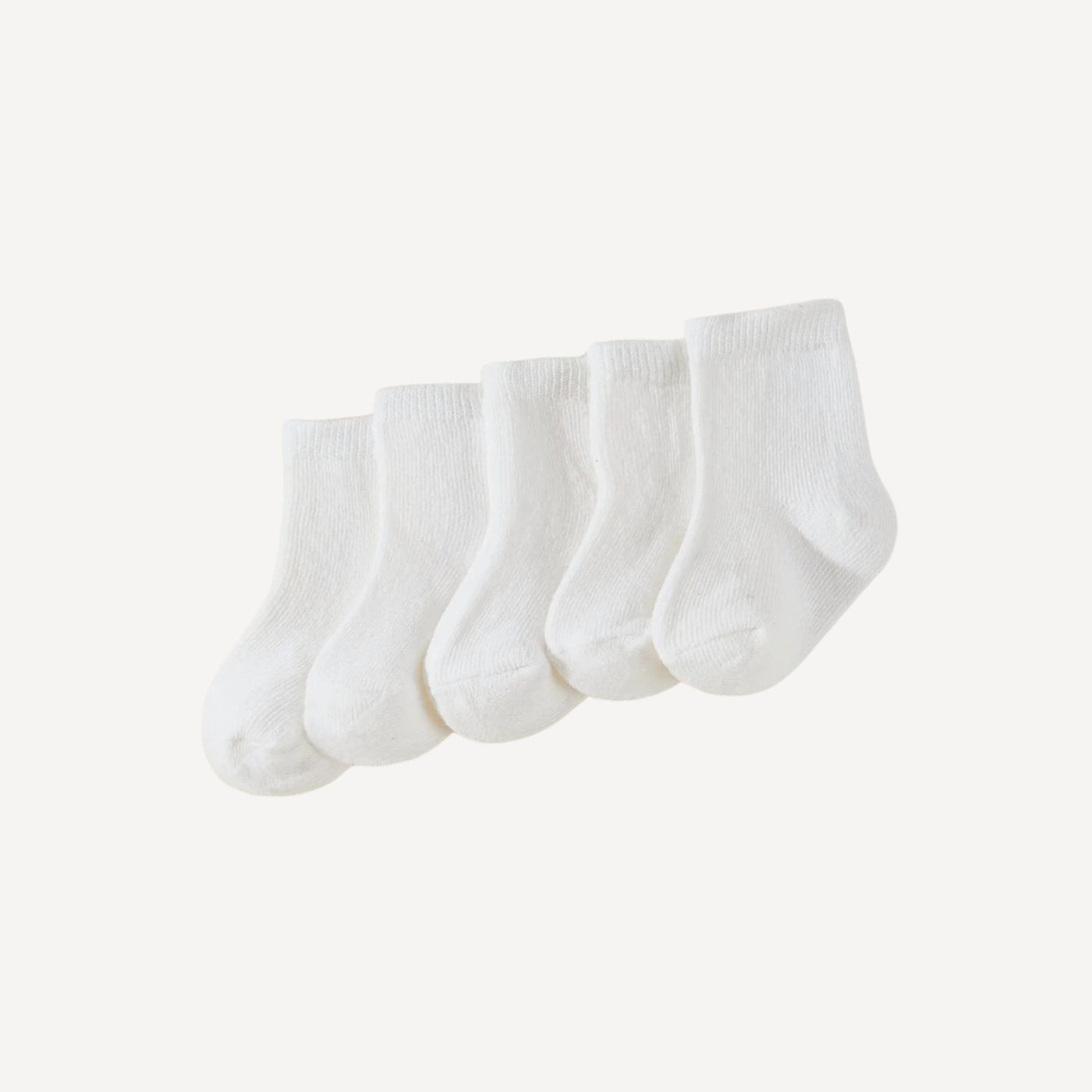 Un essentiel du trousseau : lot de trois paires de chaussettes bébé blanches, douces et confortables pour les premiers jours.