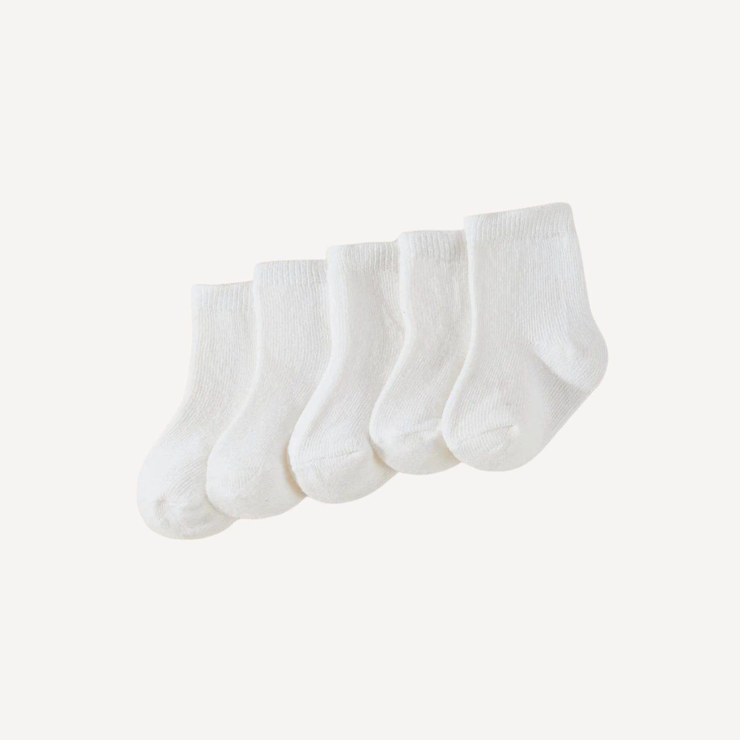 Un essentiel du trousseau : lot de trois paires de chaussettes bébé blanches, douces et confortables pour les premiers jours.