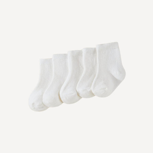 Un essentiel du trousseau : lot de trois paires de chaussettes bébé blanches, douces et confortables pour les premiers jours.