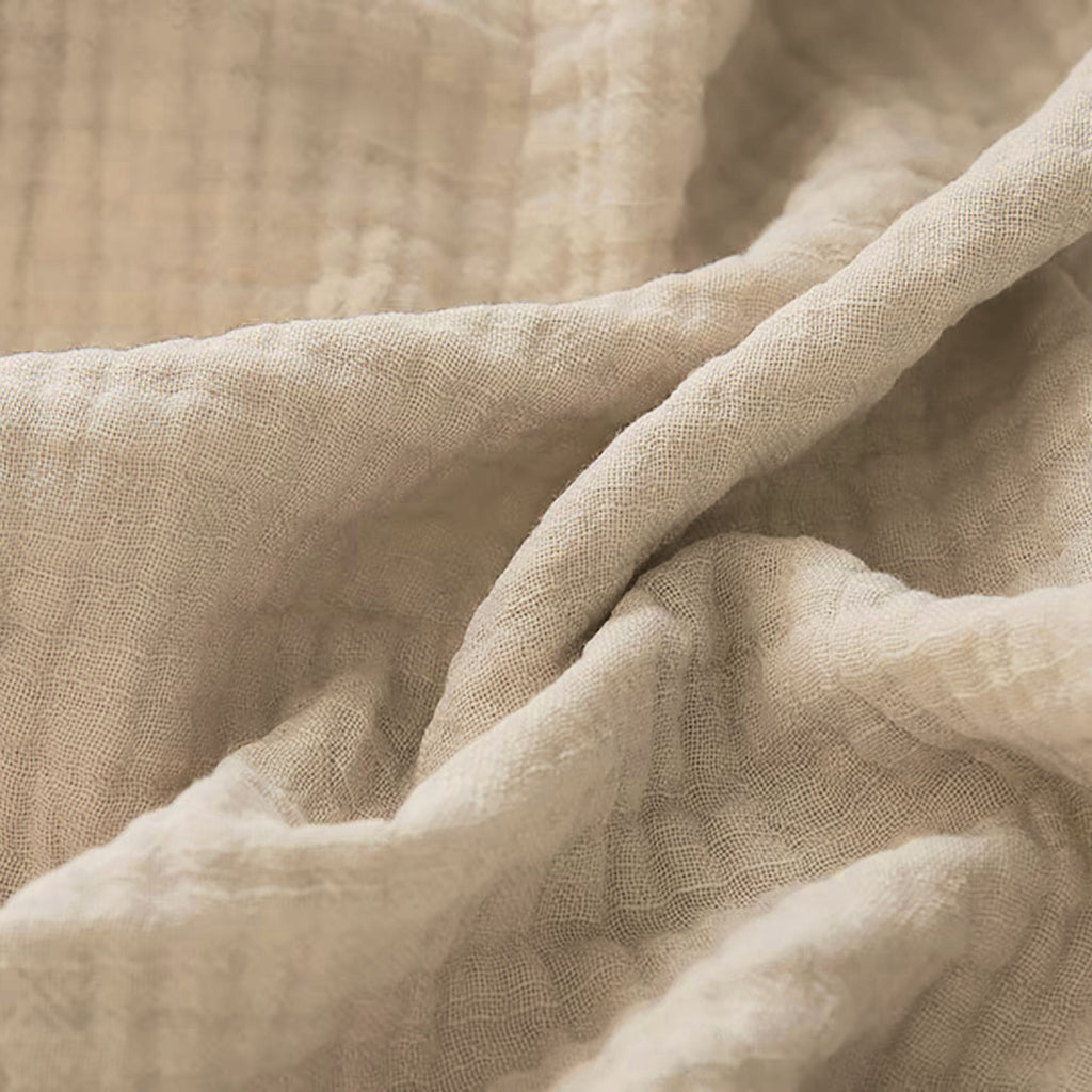 Couverture pour bébé en gaze de coton, dans un coloris kaki, avec de jolis détails visibles en zoom, pour une touche de douceur et d’élégance.