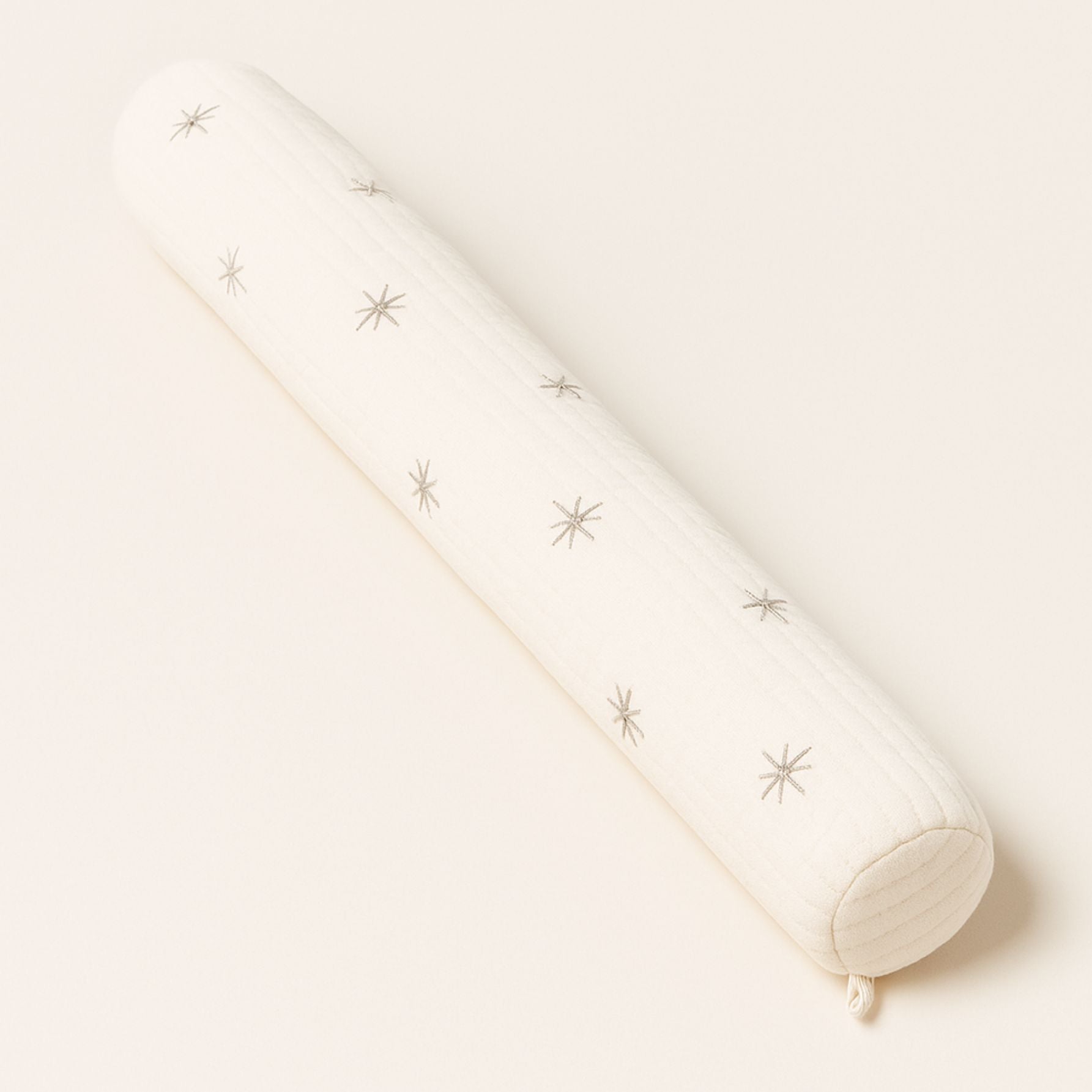 Coussin tour de lit bébé avec motif étoiles beiges sur fond crème, pour une touche poétique et apaisante dans le lit de bébé.