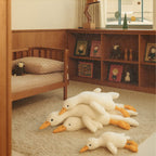 Ensemble de peluches canard Bellemoon posées sur un tapis moelleux dans une chambre en bois
